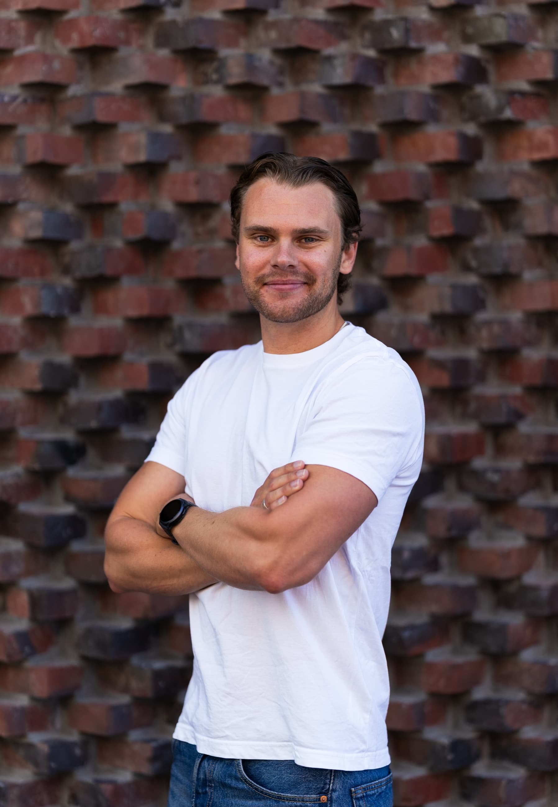 Theo Skogsberg, medgrundare av Mist Creative, med armarna i kors framför en tegelvägg.