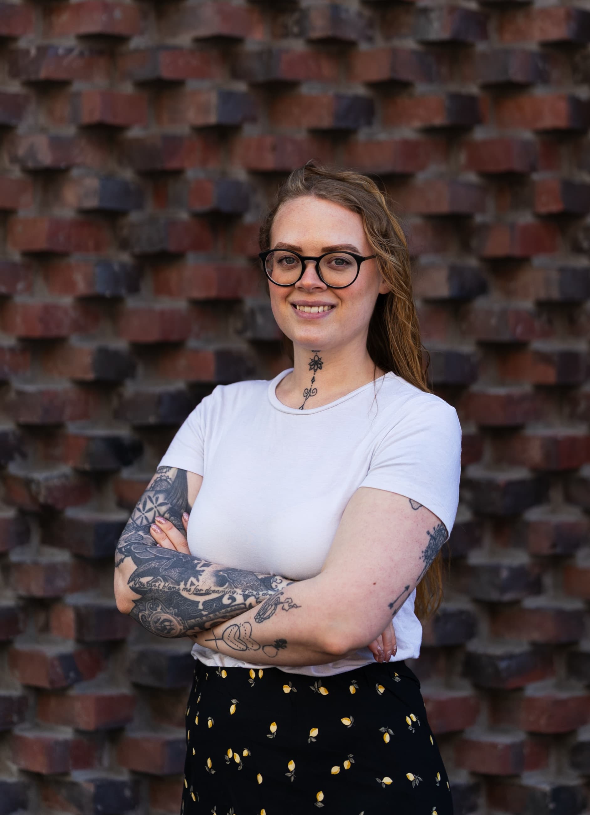 Mikaela Rasmusson, medgrundare av Mist Creative, med armarna i kors framför en tegelvägg.