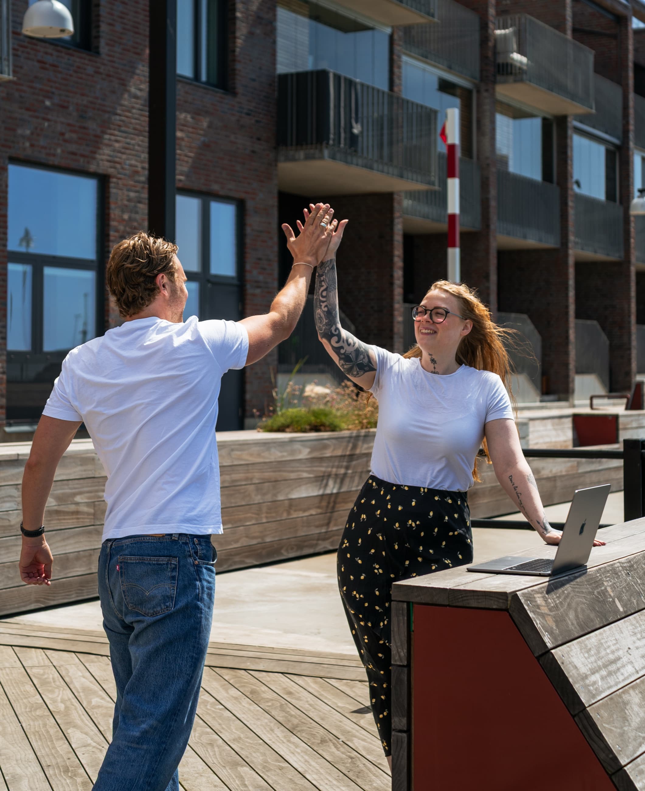 Theo och Mikaela ger varandra en high five utomhus vid en laptop i Malmö.